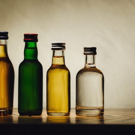 different alcohol bottles are on the table on a light background.